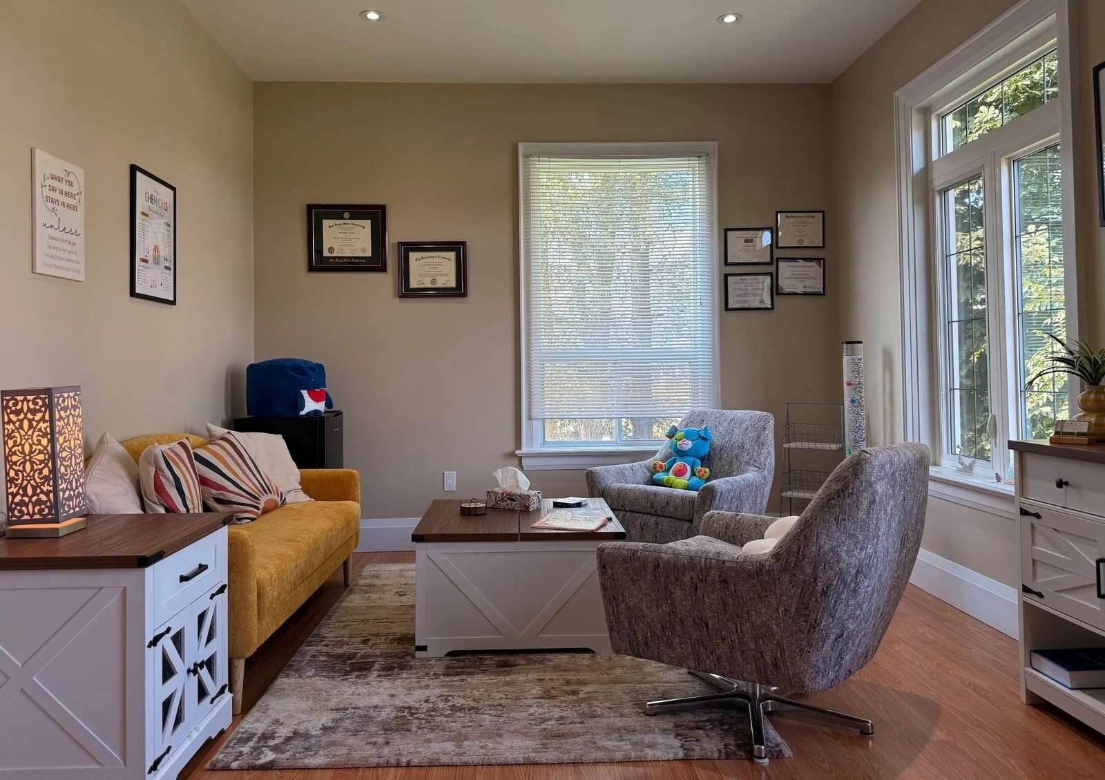 The therapy room with a sofa, armchairs, and large windows
