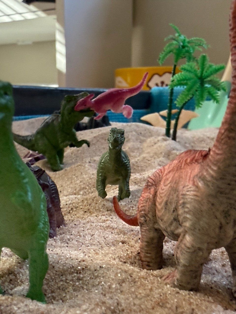 Sand tray scene with dinosaurs and palm trees