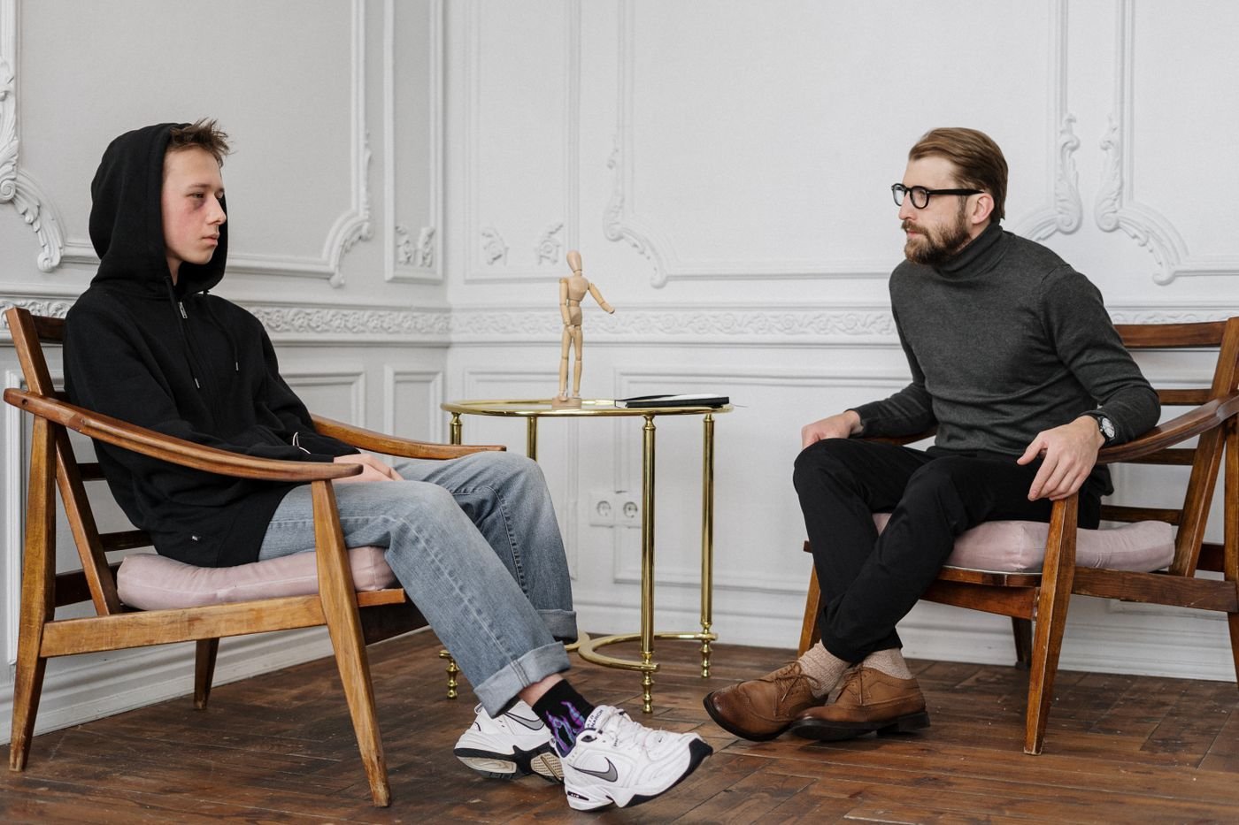 A teen in a hoodie talking with a counsellor