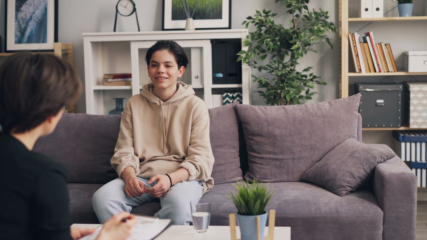 A teenager talking with a therapist on a sofa
