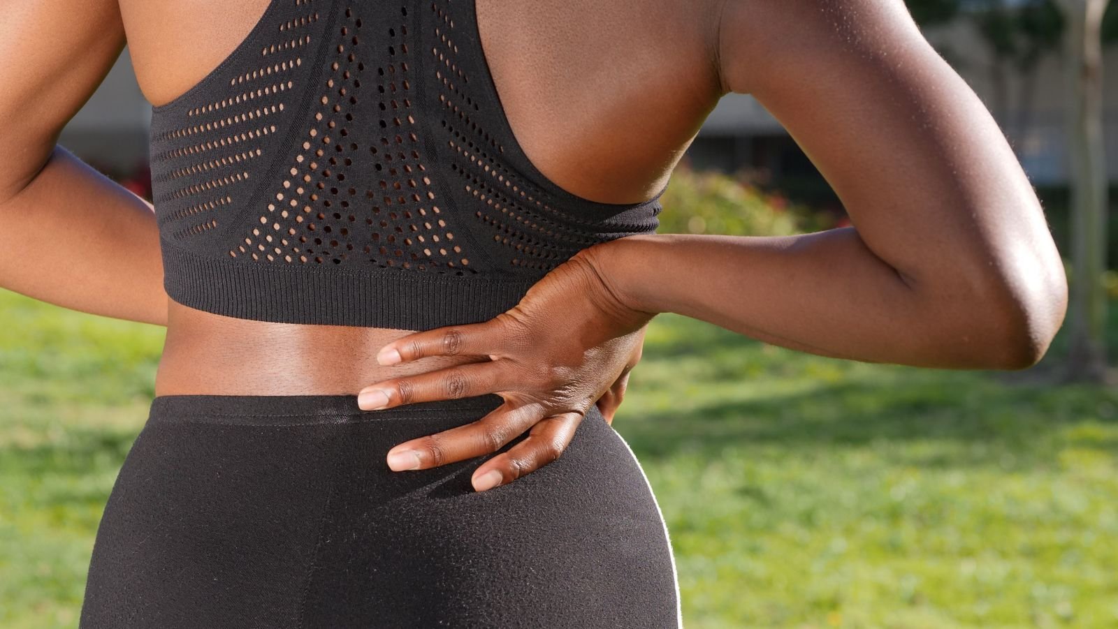 Woman in athletic wear holding her lower back