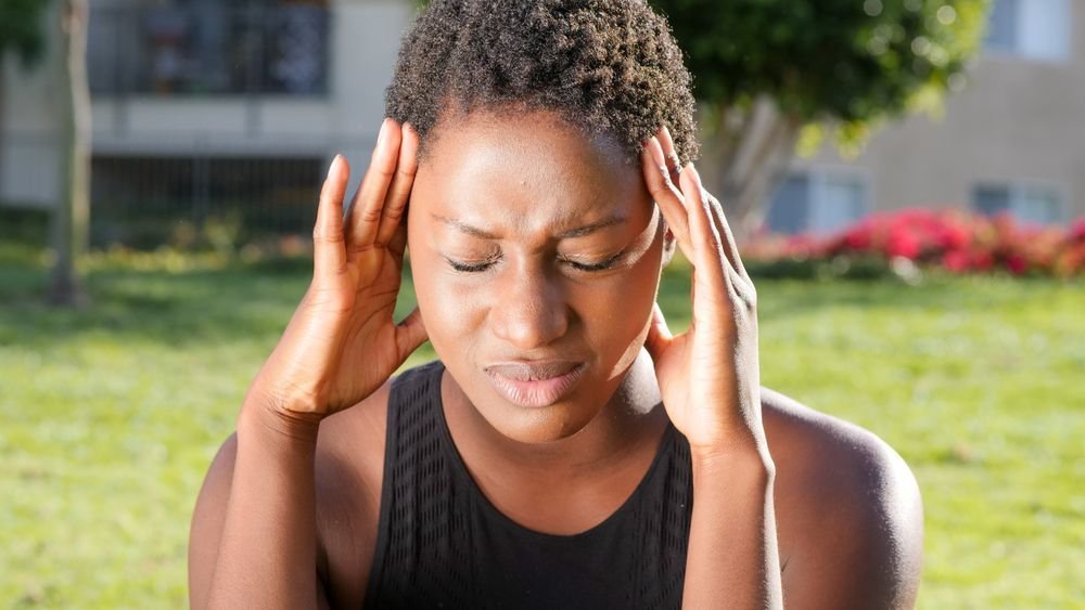 Woman pressing her temples outdoors