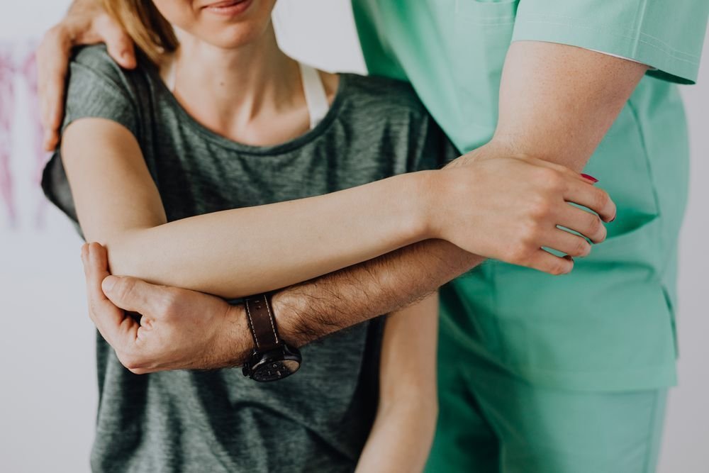 Clinician examining a patient's shoulder and arm