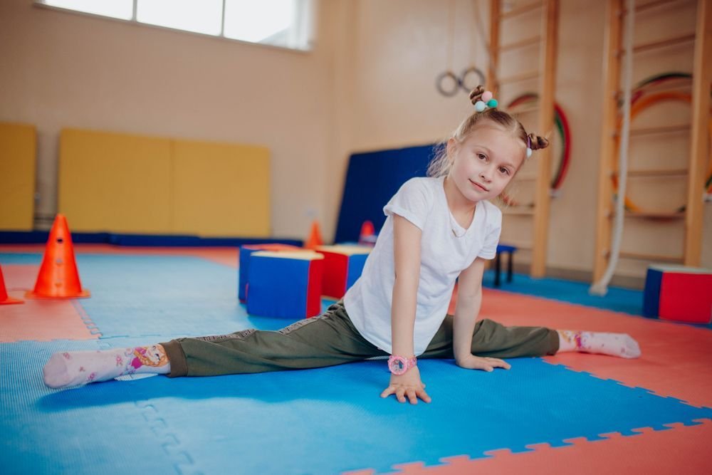 Young girl stretching on gym mats