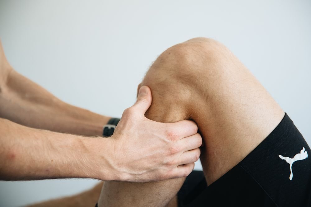 Physiotherapist's hands assessing a knee
