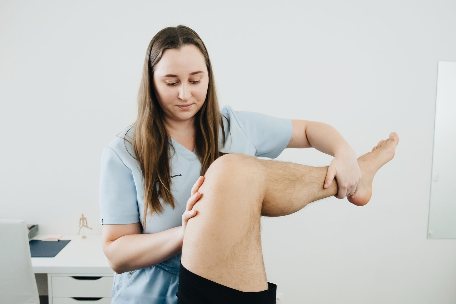 Physiotherapist bending a patient's knee during rehabilitation