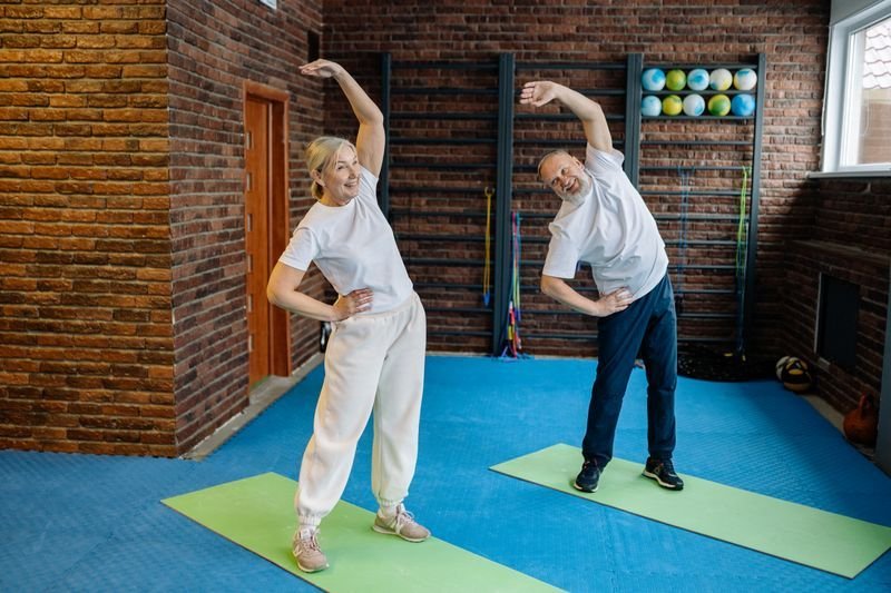 Older couple doing side stretches in a studio